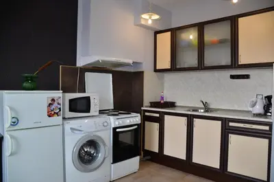 a kitchen with a washing machine and a microwave at Ivanovi Apartments in Burgas City
