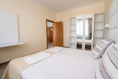 a bedroom with a white bed and a mirror at Hotel Perla Beach Club - All Inclusive in Primorsko