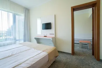 a bedroom with a bed and a desk and a television at Hotel Perla Beach Club - All Inclusive in Primorsko