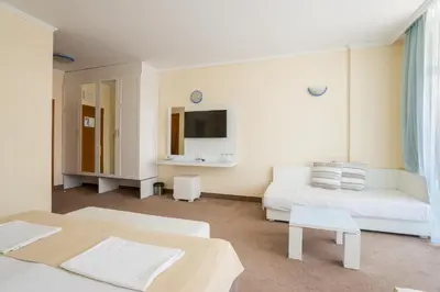 a white room with two beds and a tv at Hotel Perla Beach Club - All Inclusive in Primorsko