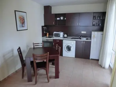 a kitchen with a table and chairs and a microwave at Sea View Crown apartment on complex with pools and beach, Sveti Vlas in Sveti Vlas