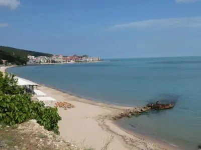 a beach with a boat in the water at Sea View Crown apartment on complex with pools and beach, Sveti Vlas in Sveti Vlas