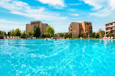 a swimming pool with blue water and buildings at Nessebar Fort Club Apartments in Sunny Beach