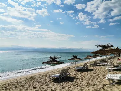 a beach with chairs and umbrellas and the ocean at Sunset House in Varna City
