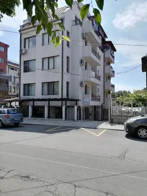 a white building with cars parked in a parking lot at White home-apartament in Burgas City