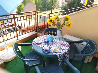 a table on a balcony with a vase of flowers at Golden Dreams Apartment in Sunny Beach