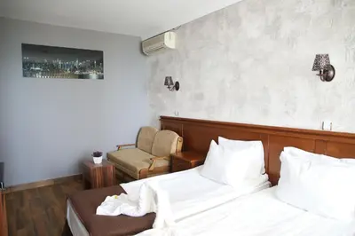a hotel room with a bed and a chair at Petrov Family Hotel in Nesebar