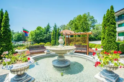a fountain in the middle of a garden with flowers at Arkutino Family Resort in Sozopol