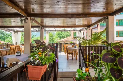 an outdoor patio with tables and chairs and plants at Arkutino Family Resort in Sozopol