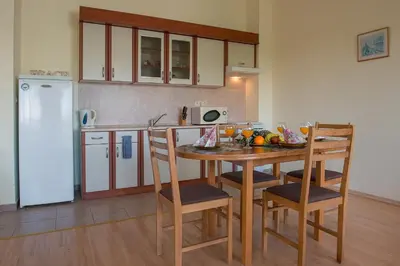 a kitchen with a table and chairs and a refrigerator at Green Fort Private Apartments in Sunny Beach