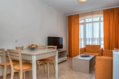 a living room with a table and chairs and a television at Royal Sun Apartments in Sunny Beach