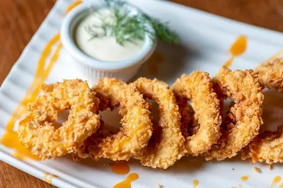 a plate of onion rings with a dipping sauce at Hotel St Valentine all inclusive in Sunny Beach
