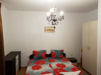a bedroom with a bed with red pillows and a chandelier at Aphrodite Rose Apartment in Sunny Beach