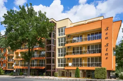 an apartment building with a tree in front of it at Hotel Sea Star Приморско in Primorsko