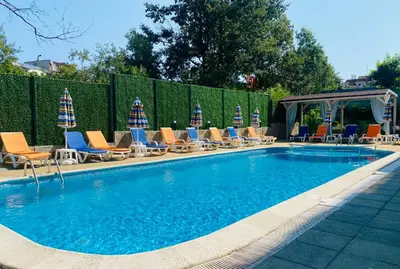 a swimming pool with lounge chairs and umbrellas at Hotel Sea Star Приморско in Primorsko