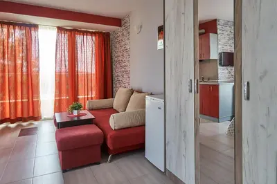 a living room with a red couch and a kitchen at Hotel Sea Star Приморско in Primorsko