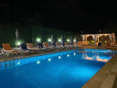 a swimming pool at night with chairs and lights at Hotel Sea Star Приморско in Primorsko