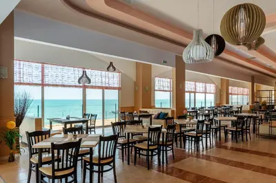a restaurant with tables and chairs and a view of the ocean at Midia Family Resort All-Inclusive in Aheloy