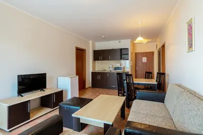 a living room with a couch and a table and a kitchen at Midia Family Resort All-Inclusive in Aheloy