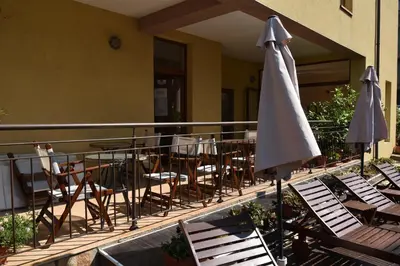 a balcony with chairs and a table and an umbrella at Kandrovi Sozopol in Sozopol