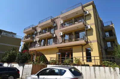 a yellow building with cars parked in front of it at Kandrovi Sozopol in Sozopol