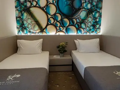 two beds in a room with a painting on the wall at Aqua Paradise Resort & Aqua Park in Nesebar