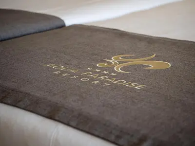 a brown mat with a gold logo on a bed at Aqua Paradise Resort & Aqua Park in Nesebar
