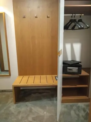 a room with a closet with a bench and a computer at Hotel Golden Tulip Varna in Varna City