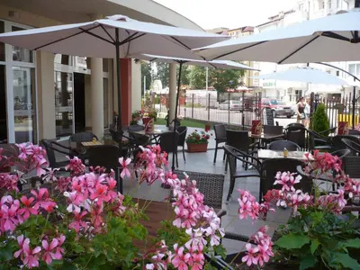 a patio with tables and chairs with pink flowers and umbrellas at Hotel Veris in Sunny Beach