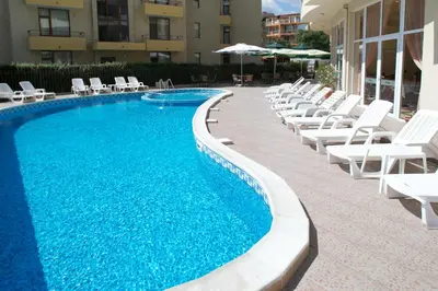 a swimming pool with white lounge chairs and a bunch ofitures at Hotel Veris in Sunny Beach