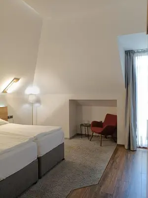 a bedroom with a bed and a red chair at Hugo Hotel in Varna City