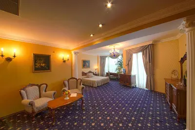 a hotel room with a bed and a table and chairs at Grand Hotel London in Varna City