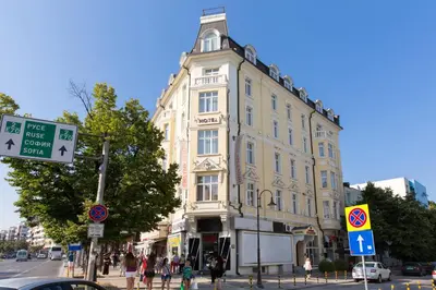 a tall yellow building on a city street with people at Boutique Splendid Hotel in Varna City