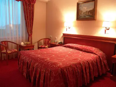 a hotel room with a bed and chairs and a window at Mirage Hotel in Burgas City