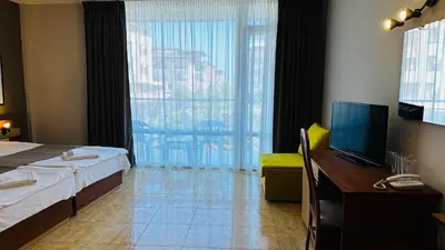 a hotel room with a bed and a desk with a television at Queen Nelly in Primorsko