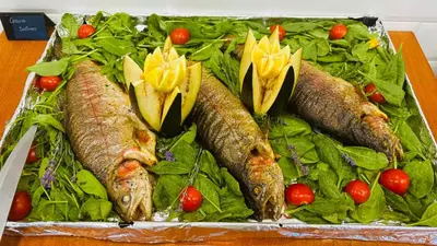 a tray of fish with lettuce and tomatoes on a table at Queen Nelly in Primorsko