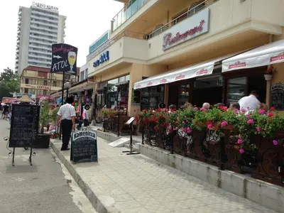 a group of people standing outside of a building with flowers at Hotel Atol in Sunny Beach