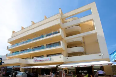 a tall building with a restaurant in front of it at Hotel Atol in Sunny Beach
