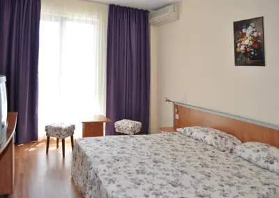 a bedroom with a bed and a window with purple curtains at Hotel Atol in Sunny Beach