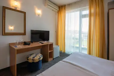 a bedroom with a desk with a television and a window at Sveti Dimitar Hotel in Primorsko