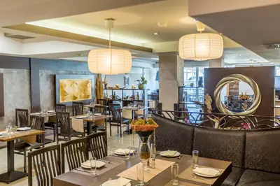 a restaurant with tables and chairs and a mirror at Selena Beach Family Hotel - All Inclusive Light in Sozopol