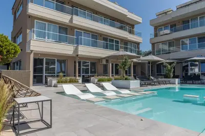 an apartment building with a swimming pool and lounge chairs at Selena Beach Family Hotel - All Inclusive Light in Sozopol