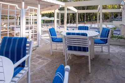 a patio with blue and white chairs and a table at Ariana Hotel in Kiten