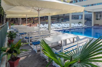 a pool with white tables and chairs next to a pool at Ariana Hotel in Kiten
