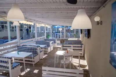 a restaurant with white tables and chairs and lights at Ariana Hotel in Kiten