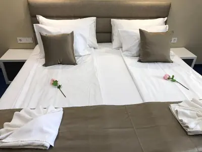 a large white bed with two flowers on it at Family Hotel Avenue in Kiten