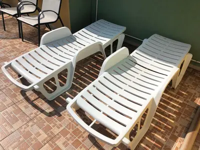 three white lounge chairs sitting next to a wall at Family Hotel Avenue in Kiten