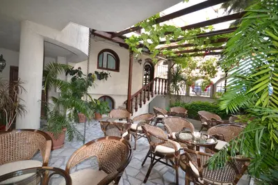 an outdoor patio with tables and chairs and plants at More Family Hotel in Sozopol