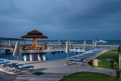 a pool with chairs and umbrellas next to the beach at Obzor Beach Resort in Obzor