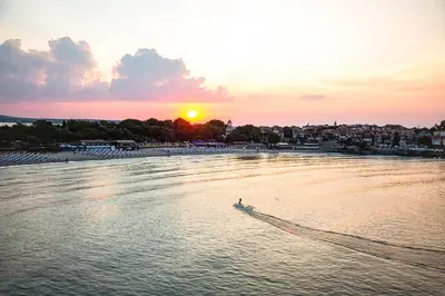 a person in a boat on the water at sunset at Hotel Antea - By The Sea in Sozopol